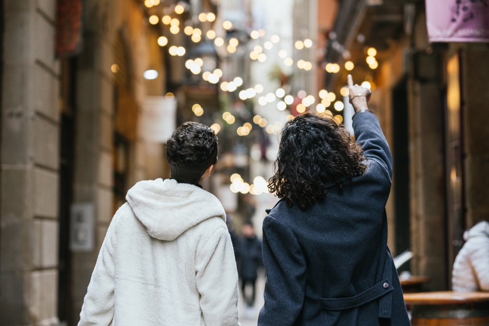 Gay,Couple,Walking,And,Pointing,At,Christmas,Lights,In,Barcelona