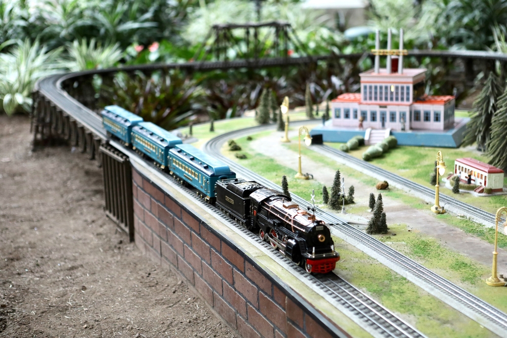 Maquette de train dans un décor de jardin, mettant en scène une miniature